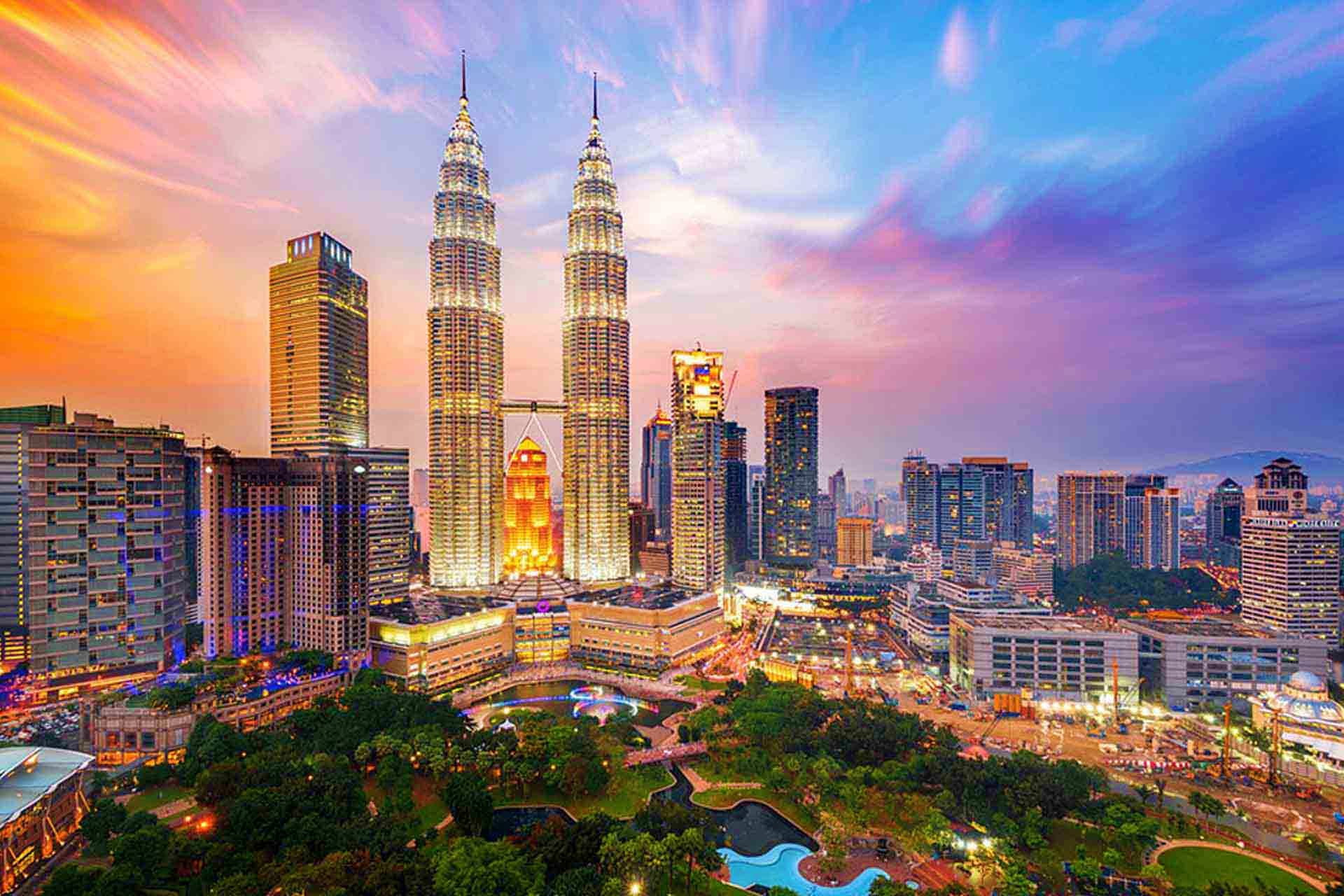 Kuala Lumpur skyline at sunset featuring the illuminated Petronas Twin Towers and surrounding cityscape at dusk